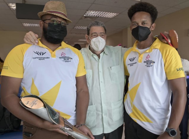 Prime Minister, Dr Hon Ralph Gonsalves is flanked by QBR team members Shimano Bailey (with Baton in hand) and Claude Bascombe.