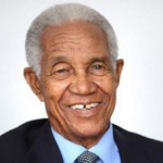 Smiling portrait of Sir Garfield Sobers of Barbados in a dark suit.