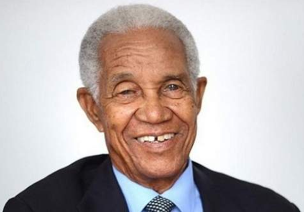 Smiling portrait of Sir Garfield Sobers of Barbados in a dark suit.